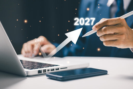 Business professional uses laptop and stylus with a rising arrow toward 2027, illustrating business growth, future planning, strategy, forecast, progress, and financial success concept.