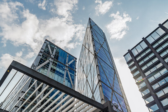 View of The Leadenhall Building with its distinctive tapered glass facade and steel structure rising against a blue sky in London, England, United Kingdom.