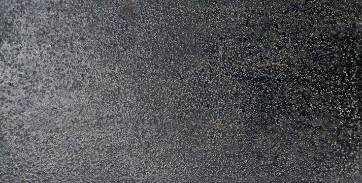 Dark grey rough stone surface texture background, close up grainy charcoal granite or concrete background. Dark cast iron metal surface texture, rough black metallic background with speckled pattern.