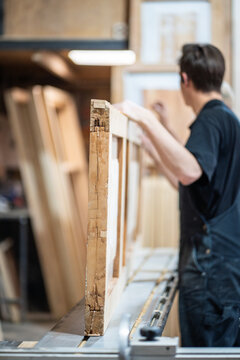 Antique wooden door restoration process in small business carpentry workshop, focused craftsperson restorer working at workbench with furniture, handmade renovation and craft in woodworking studio.