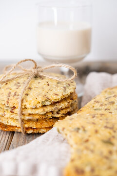 Healthy food. Grain pastry. Round crackers stack tied with jute placed on counter. Tasty cookies flax pumpkin seeds with yogurt glass.