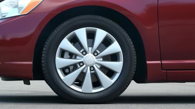 Close-Up of a Red Sedan Wheel Rolling Into Frame