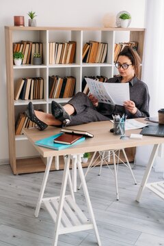 Corporate lifestyle. Employee routine. Pensive female manager analyzing business document using notebook laptop at desk at office.