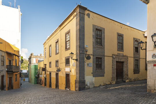 View of the historic yellow colonial-style building with stone corner details and wooden windows in the Vegueta district of Las Palmas de Gran Canaria, Canary Islands, Spain.