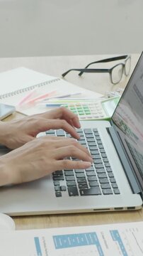 Close-up of Japanese businesswoman hands working on computer by window, vertical video