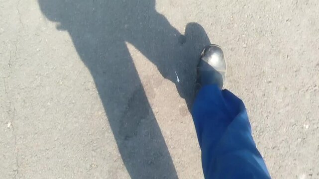 a man wearing trousers and shoes is walking briskly in asphalt street