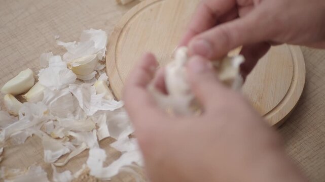 Hands peeling garlic on wooden board