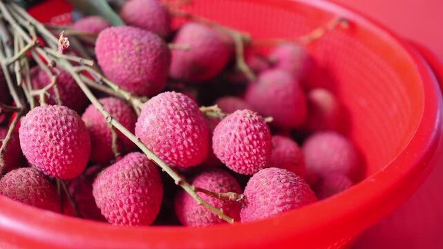 Fresh lychee in a red basket at a market