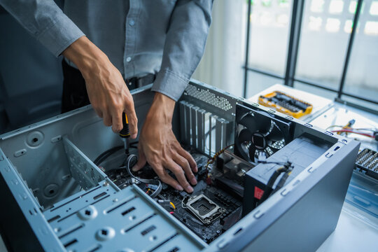 Asian IT engineer man fixing mainboard in pc case on working table