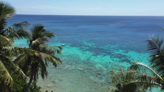 Aerial view of paddleboarding at a beautiful tropical beach with turquoise waters and coconut trees in Sabang, Aceh, Indonesia.
