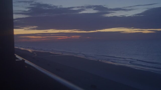People walking on the beach at dawn in Surfside, South Carolina with wide stable view.