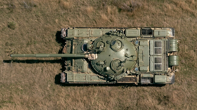 Military Tank on Dry Terrain: An overhead view of a powerful military tank positioned on a field of dry grass, showcasing its formidable machinery and robust design.