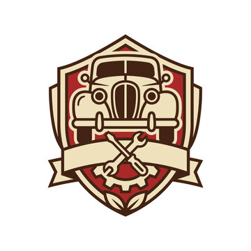 Automotive shield logo with classic car and wrenches.