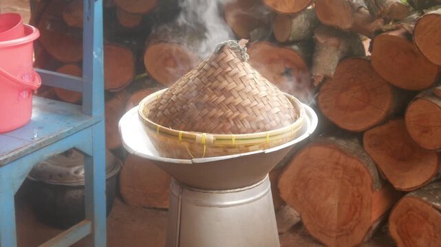 Cooking rice traditionally using a pot and a bamboo steamer over a wood fired stove.