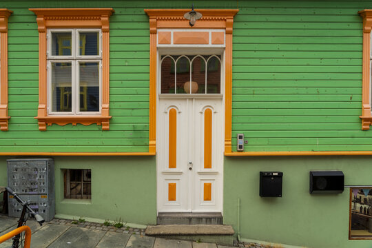 View of a colorful wooden house facade with green siding and bright orange trim in the historic old town of Stavanger, Rogaland, Norway.