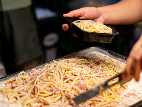 Vendor Pouring Creamy Sauce Over Spaghetti in Takeaway Box Street Food