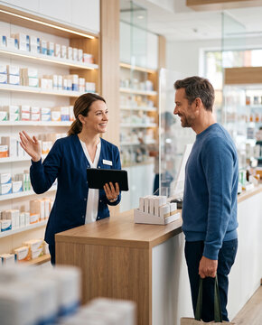 Pharmacist explains over-the-counter healthcare options to customer in modern pharmacy, supporting medication guidance, wellness, patient service and informed health decisions with copy space.