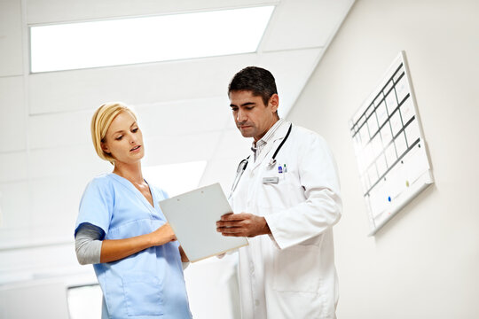 Clinic, team and talk with medical checklist for case discussion, test results or doctor advice. Nurse, people and clipboard on low angle for health records, treatment options and care coordination