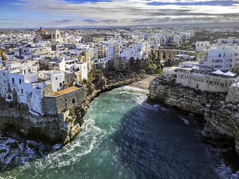 Aerial view of the historic town of Polignano a Mare with its white buildings perched on dramatic limestone cliffs above the turquoise Adriatic Sea in Polignano a Mare, Apulia, Italy.