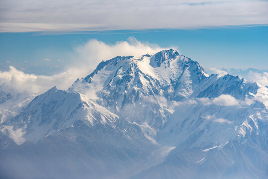Aerial view of Nanga Parbat, the ninth highest mountain in the world, featuring snow-capped peaks, rugged glaciers, and surrounding clouds in the Himalayas, Gilgit-Baltistan, Pakistan.