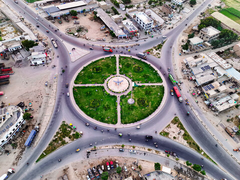 Aerial view of Pakistan Chowk featuring a fighter jet monument in the center of a landscaped roundabout surrounded by urban roads and buildings, Dera Ghazi Khan, Punjab, Pakistan.