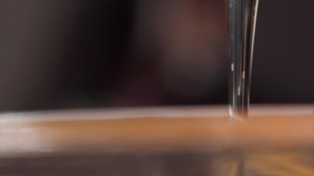 Macro close up of golden honey dripping in a continuous stream, capturing natural flow and viscosity during slow motion for food and cooking concepts