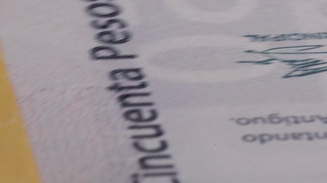 Macro close up of a spinning Mexican 50 peso banknote highlighting engraved details, printed patterns and security elements during continuous rotation