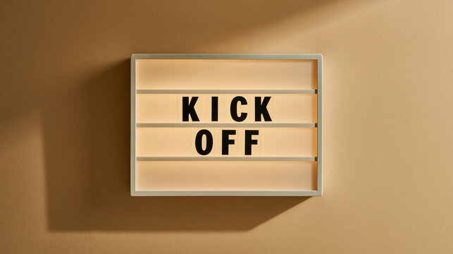 Kick Off Meeting Sign: A glowing light box displaying KICK OFF rests on a neutral background, symbolizing the beginning of a new project or venture.