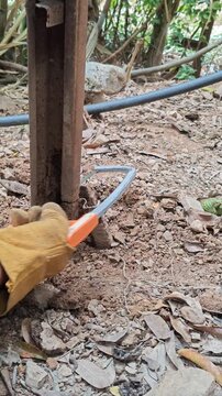 cutting iron buried in the ground with a hacksaw