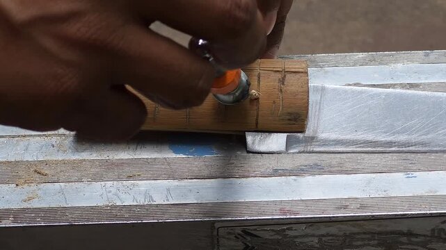 Adjusting a small clamp onto a bamboo knife handle to secure glued wood pieces