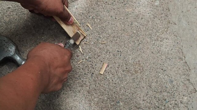 Hands holding a bamboo wood piece and removing splinters using a chisel tool