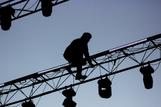 trabajador de alto riesgo instalando luces de escenario