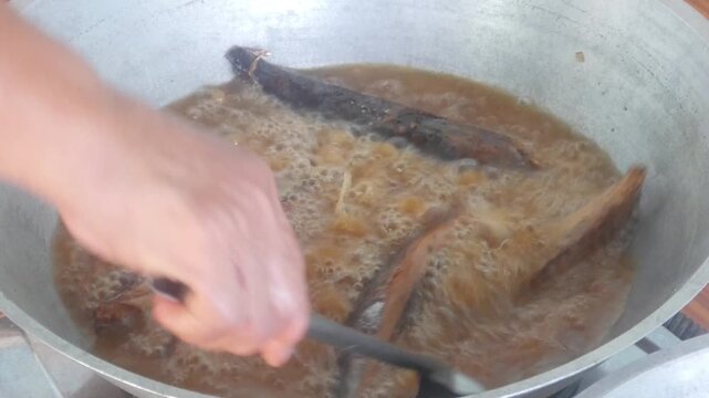 frying mackerel tuna in a large wok with hot oil