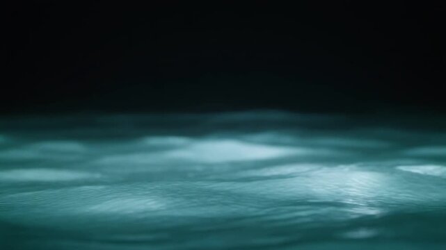 Aqua-toned water weaves through continuous gentle currents, light revealing moving surface texture and subtle depth against near-black with calming natural atmosphere and smooth motion.