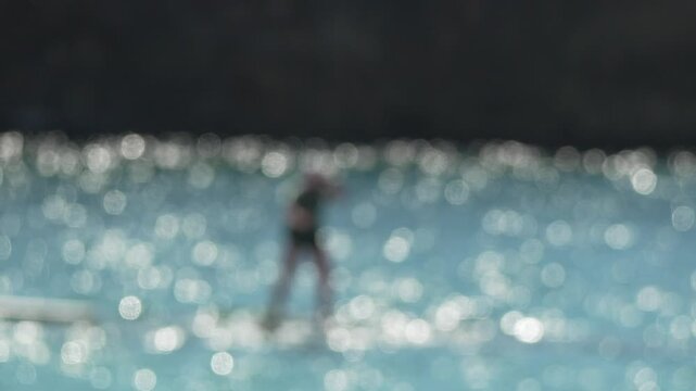 Bright Bokeh Paddleboarding Silhouetted Figure Paddling on Sparkling Blue Water