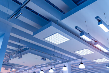 Obraz premium Directional LED lights on rails under the ceiling in a modern warehouse, shopping center building, office or other commercial real estate object.
