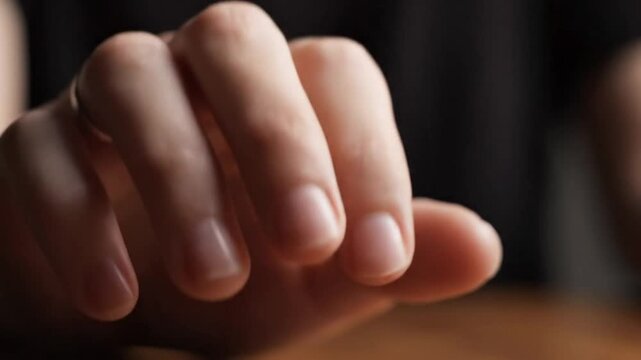 Close up of a persons clenched fist in a dark setting.