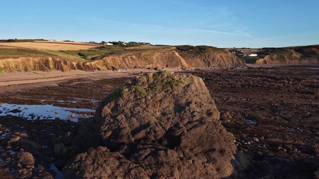 Drone flight around Black Rock on the Cornish coast at Widemouth Bay with evening light