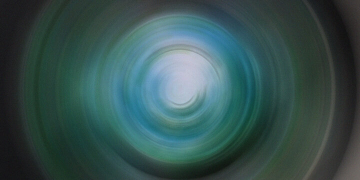 Abstract circular motion vortex effect with blue and green light rays.