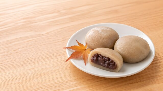 白い皿に盛ったとち餅 粒あんの断面ともみじを添えた秋の和菓子