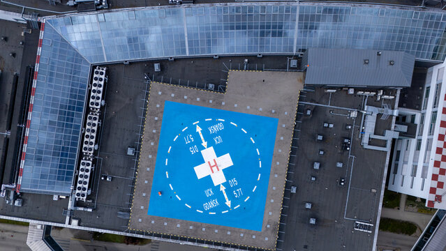 Aerial view of the hospital helipad with a blue landing surface and white H markings on the roof of the University Clinical Centre in Gdansk, Poland.
