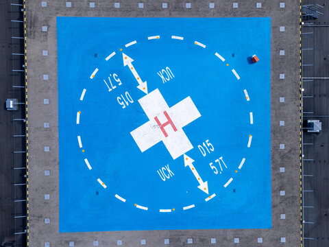 Aerial view of a blue hospital helipad with a white H marking, directional arrows, and technical specifications in Gdansk, Poland.