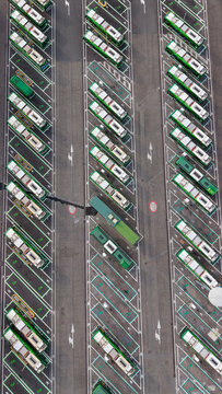 Aerial view of an electric bus depot with multiple green buses parked in designated bays at a modern public transport facility in Milan, Lombardy, Italy.