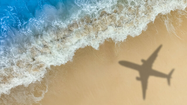 Aerial view of shadow passenger plane silhouette and sandy beach blue sea with waves at sea beach summer vacation sea travel concept	