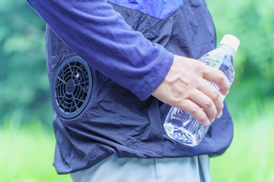 熱中症対策｜ファン付きウェアを着でペットボトルの水を持つ男性