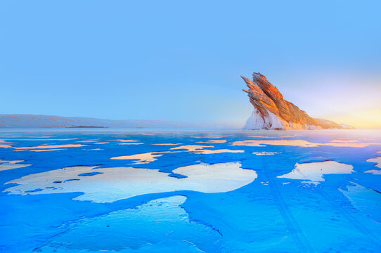Beautiful winter landscape of frozen Lake Baikal at sunrise - A granite rock with steep slopes rises above a frozen lake - Baikal lake, Siberia