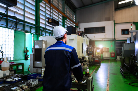 Industrial worker operating cnc machine equipment in modern manufacturing plant for industrial automation concept.