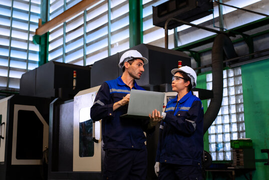 Engineers using laptop for machinery diagnostics and maintenance check in industrial plant
