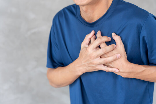 hand hold chest with heart attack symptoms, man have chest pain caused by heart disease, leak, dilatation, enlarged coronary heart, press on the chest with a painful expression