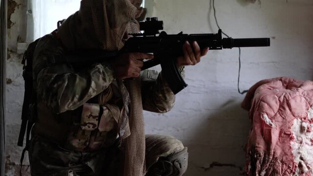 A soldier in camouflage clothing takes his weapon off safety, cocks the bolt, then raises his automatic rifle and aims at the enemy. He raises his rifle, ready to take aim at an unseen enemy.